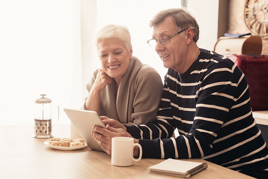 Blog - Senior Couple at Their Kitchen Island Sharing Scones and French Pressed Coffee While Reading a Tablet Together